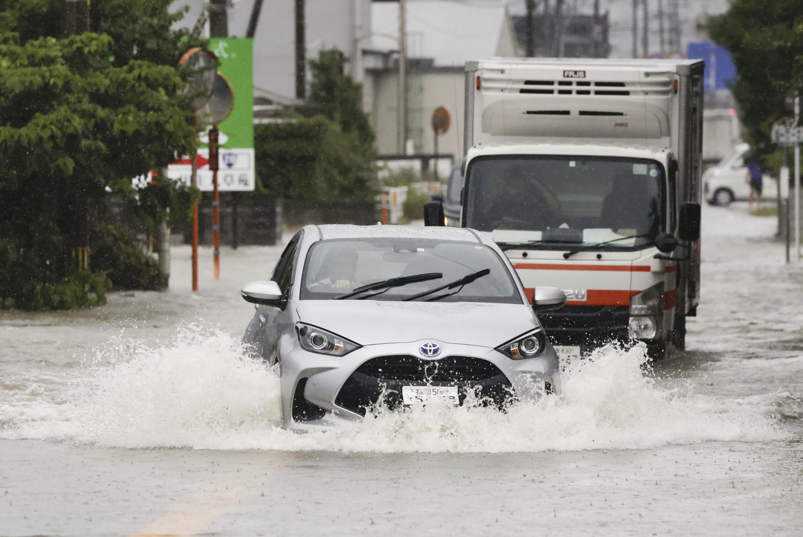 Vehicles shift through a flooded street in Kurume, Fukuoka prefecture, southern Japan Monday, July ...