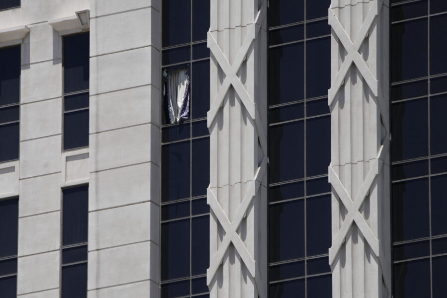 A curtain hangs out of a broken window on a hotel tower at Caesars Palace Hotel & Casino, Tuesday, ...