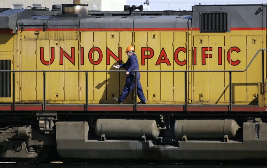 A maintenance worker walks on the side of a locomotive in the Union Pacific Railroad fueling yard i...