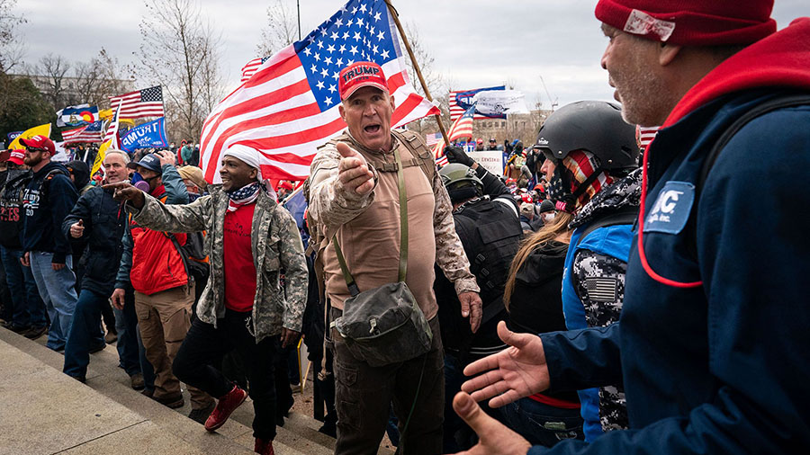Ray Epps, in the red Trump hat, center, gestures to others as people gather on the West Front of th...