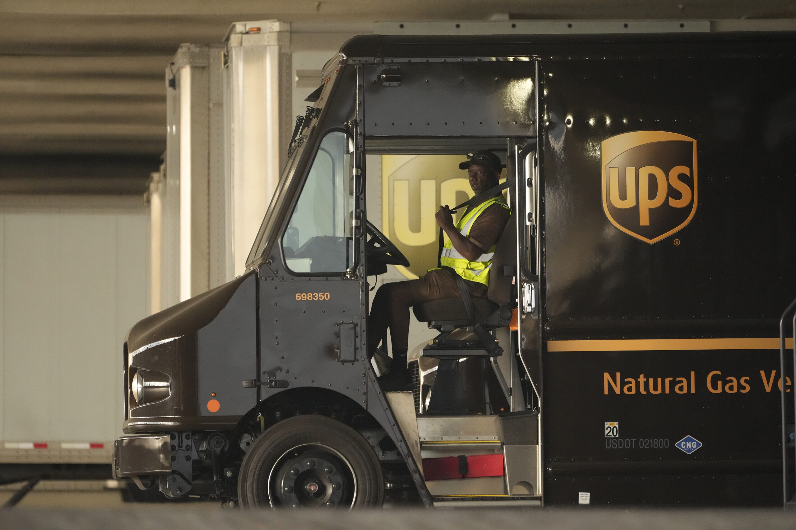 FILE - A UPS driver puts his seat belt on before driving off as UPS workers hold a rally in downtow...