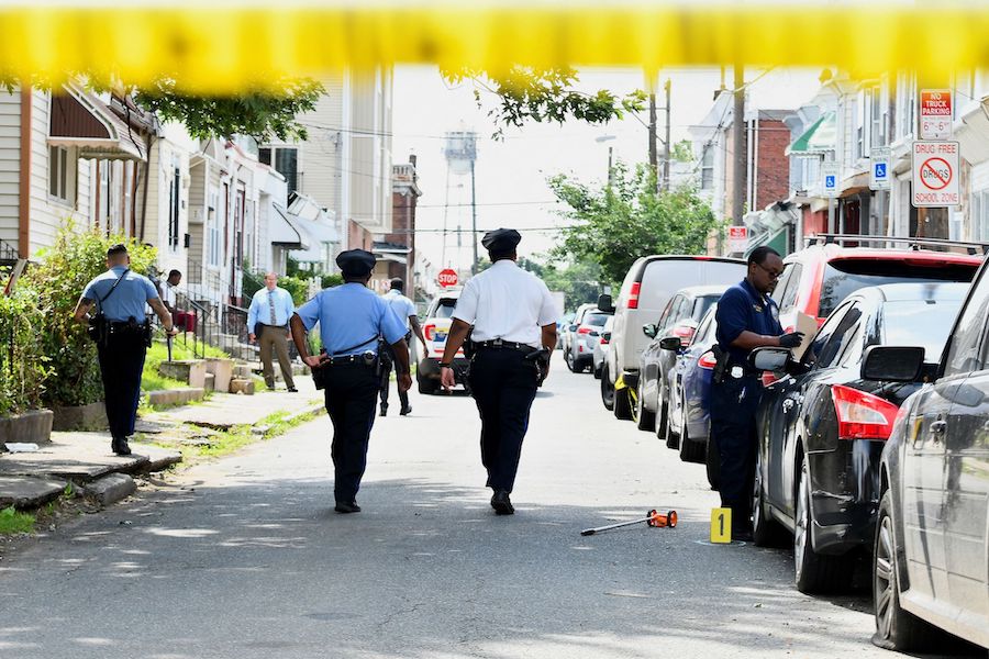 Police officers on July 4 investigate the scene of Monday night's mass shooting in southwest Philad...