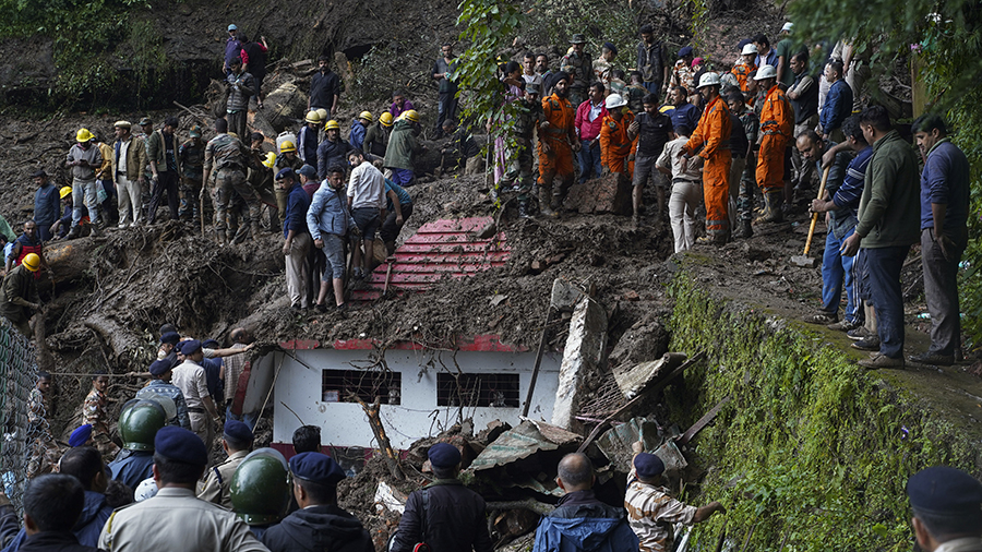Rescuers remove mud and debris as they search for people feared trapped after a landslide near a te...