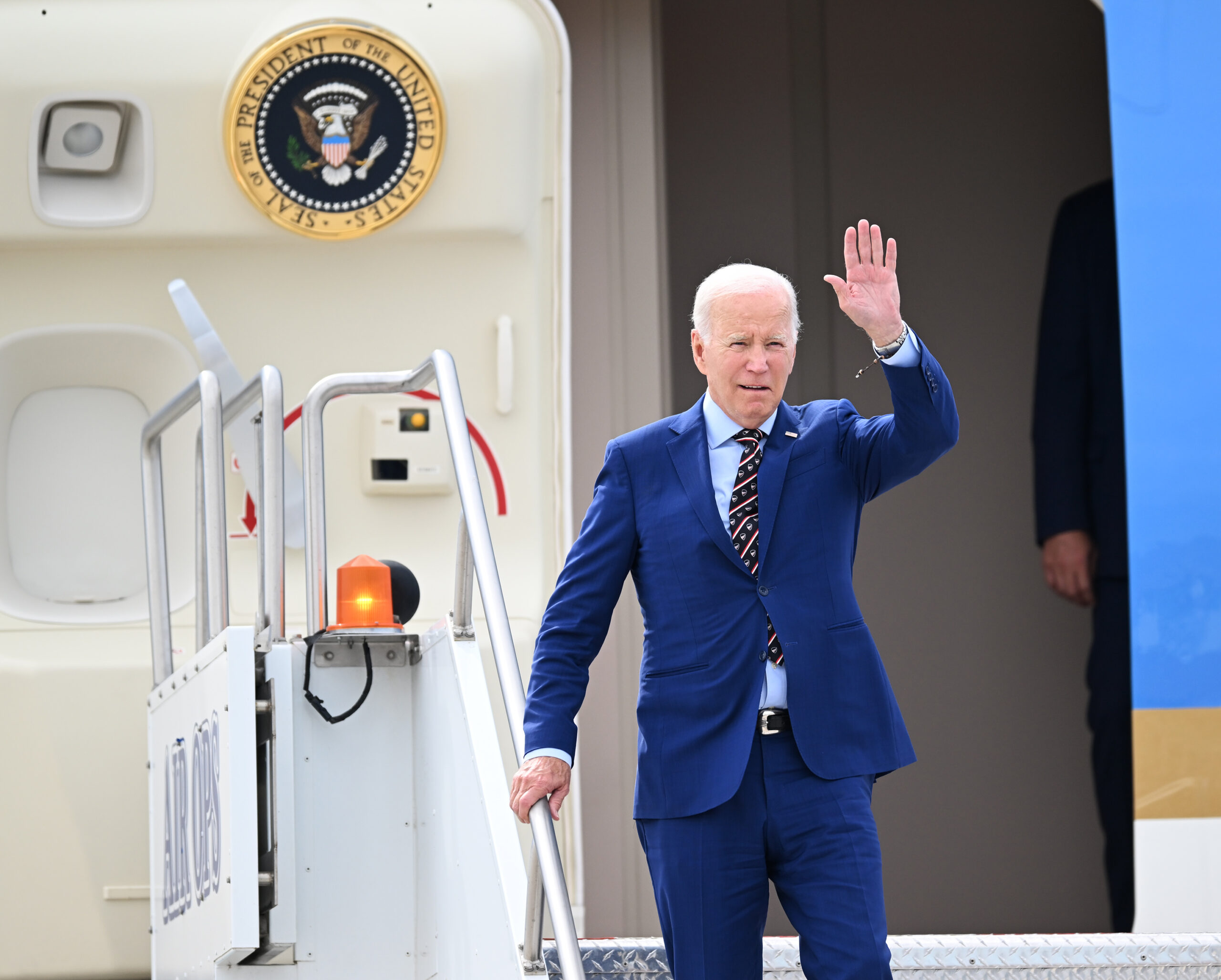 President Joe Biden waves toward the media as he arrives on Air Force One at Roland R. Wright Air N...