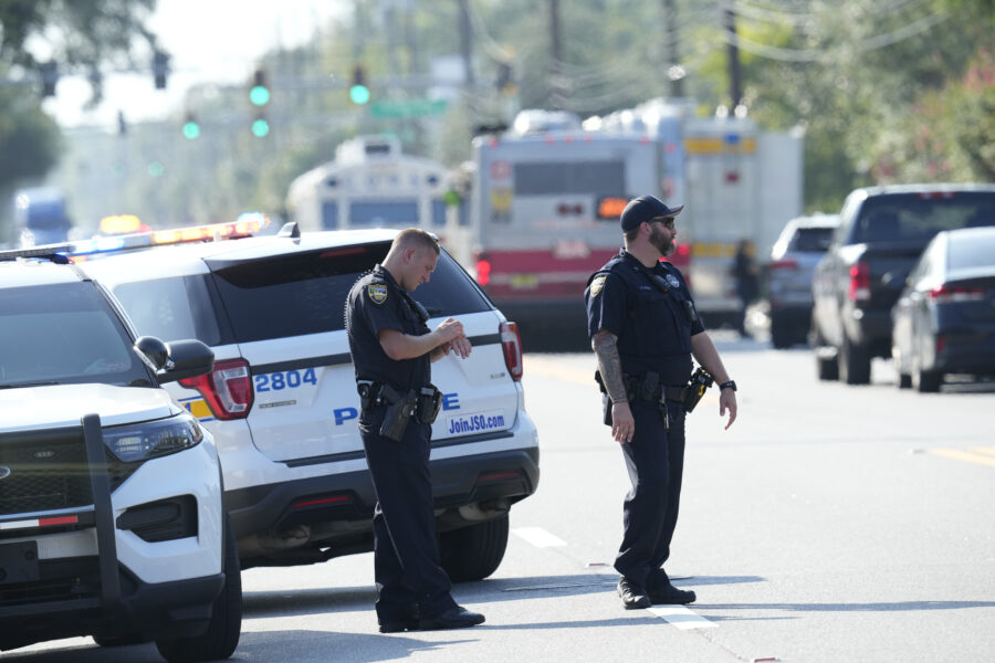 Jacksonville police officers block the perimeter of the scene of a mass shooting, Saturday, Aug. 26...