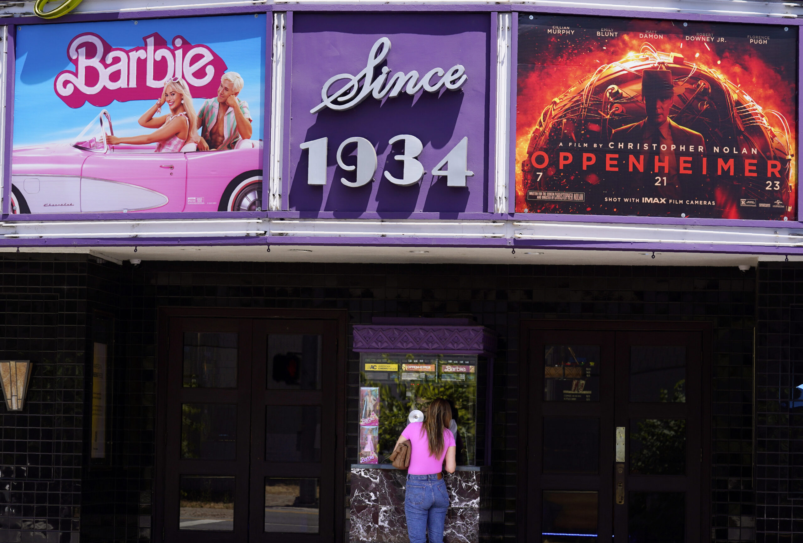 A patron buys a movie ticket underneath a marquee featuring the films "Barbie" and "Oppenheimer" at...