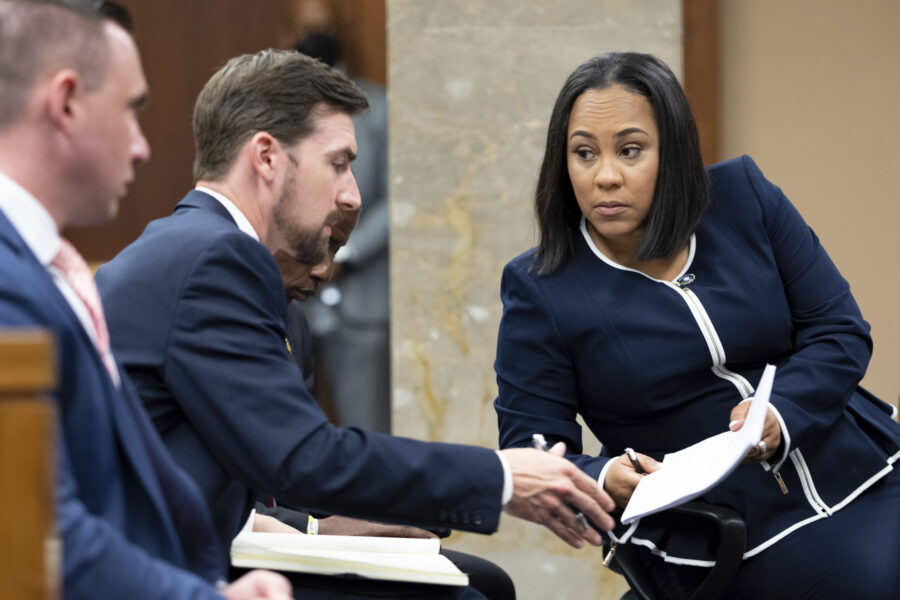 FILE - Fulton County District Attorney Fani Willis, right, talks with a member of her team during p...