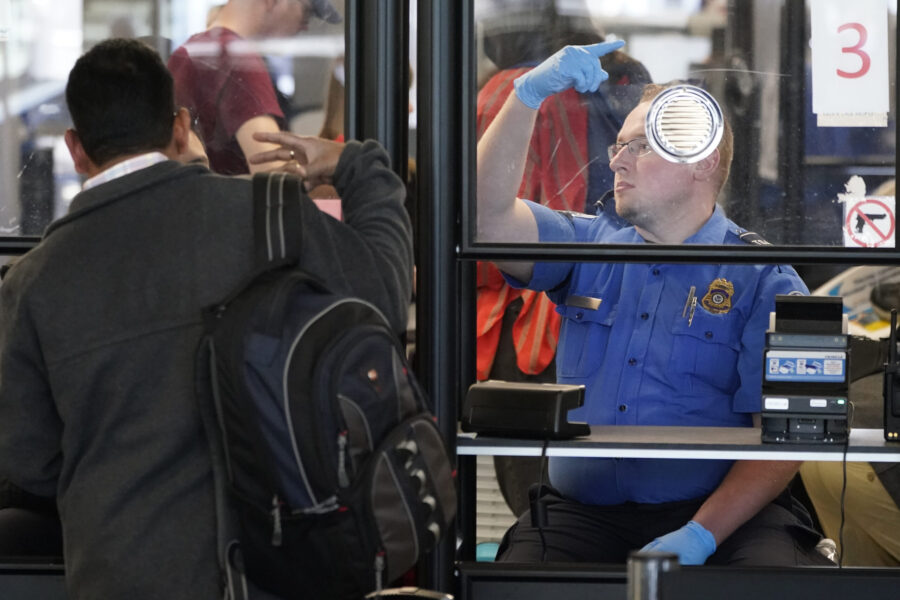 FILE - A Transportation Security Administration agent signals for the next airline passenger in lin...