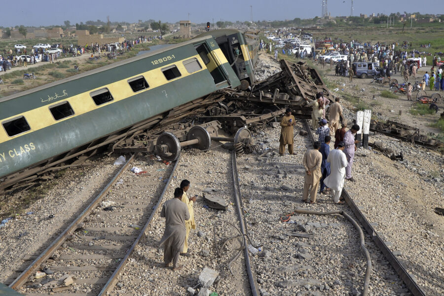 Local residents examine damaged cars of a passenger train which was derailed near Nawabshah, Pakist...