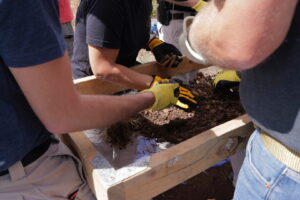 men and women sorting through dirt at a possible burial site
