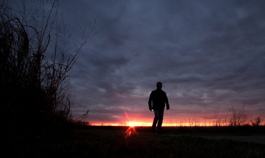 FILE - In this Nov. 20, 2015 file photo, a man walks along a trail during sunset near Manhattan, Ka...