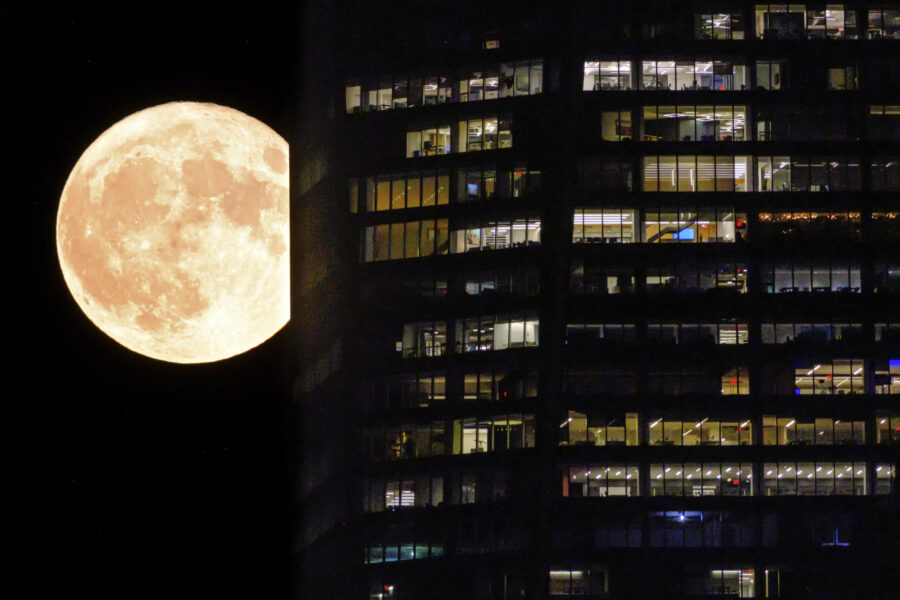 FILE - A supermoon passes behind the illuminated windows of a New York City skyscraper, Aug. 1, 202...