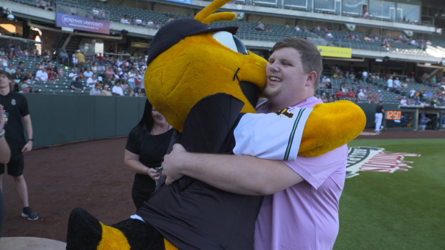 The Bees' mascot hugs and kisses Mason Hansen after he performs the game's first pitch. (University...