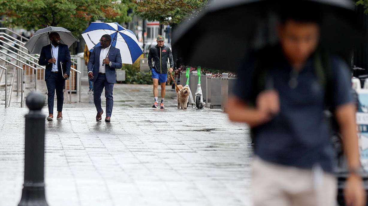 People walk in the rain in Salt Lake City on Aug. 22. More rain and lower temperatures are in the f...