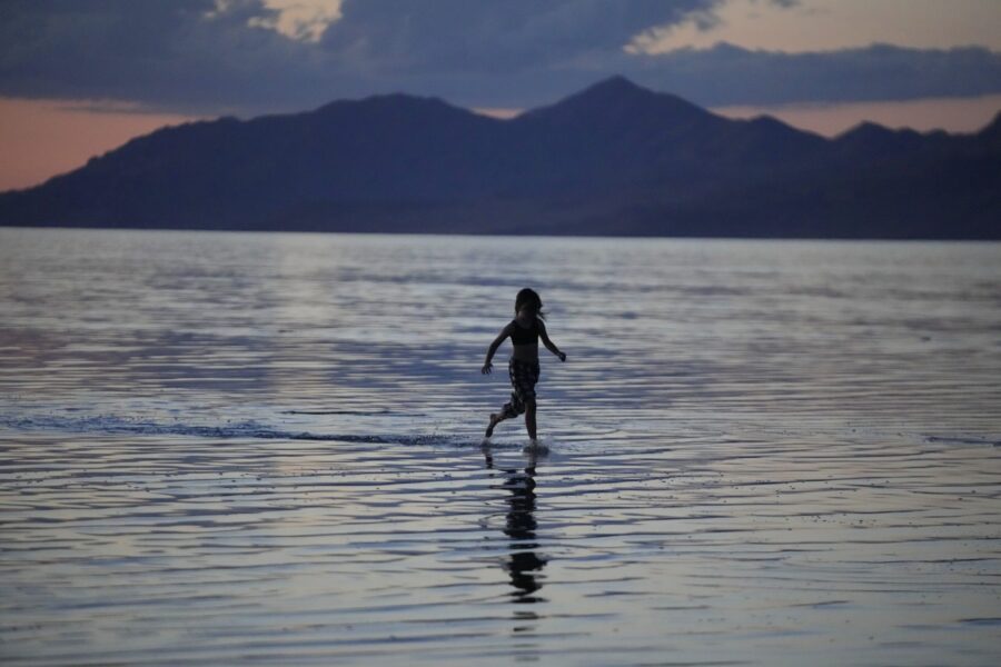 FILE - A young person runs through the Great Salt Lake on June 15, 2023, near Magna, Utah. A coalit...