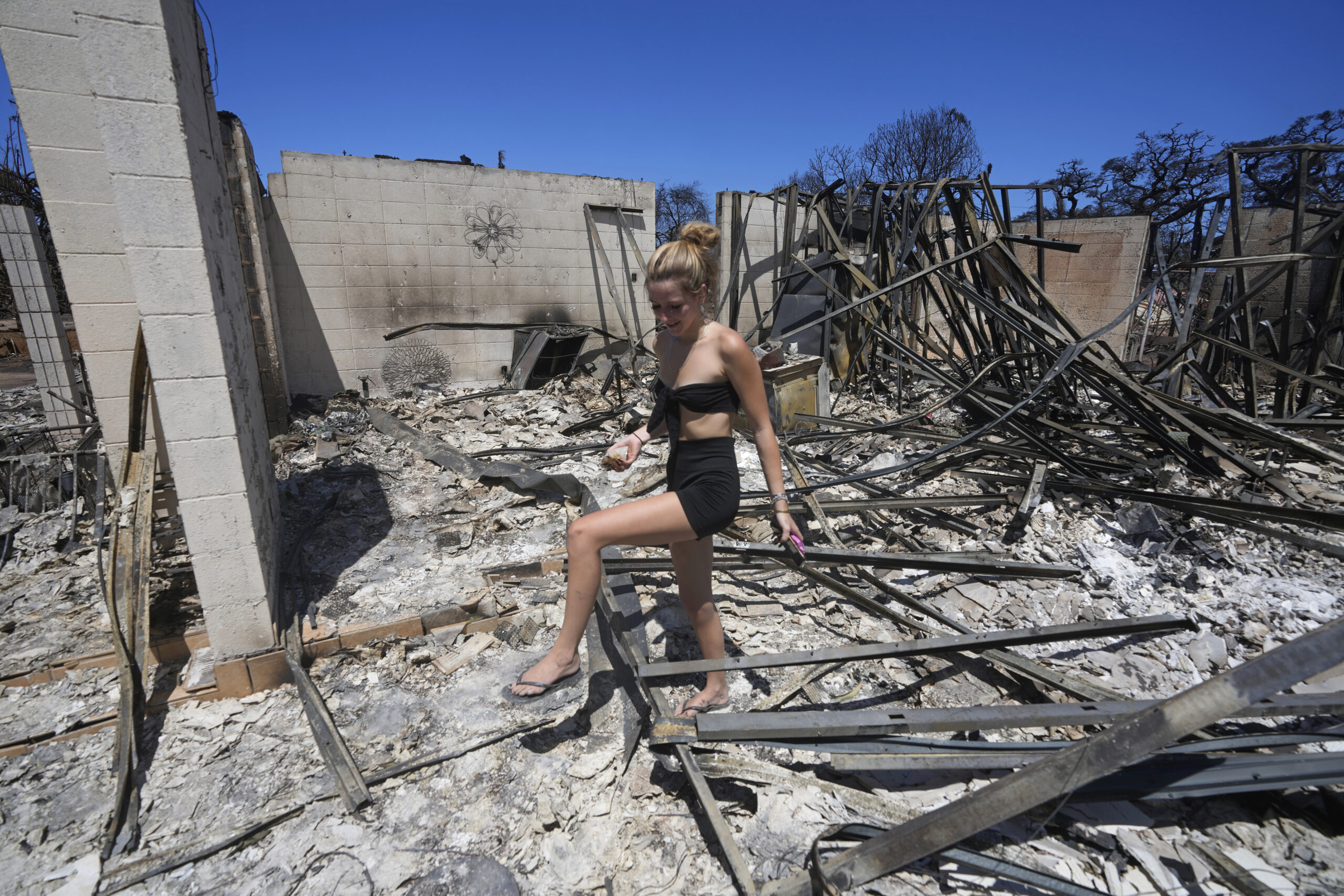 FILE - Sydney Carney walks through her home, which was destroyed by a wildfire on Aug. 11, 2023, in...