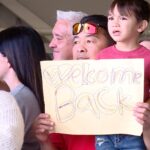 A family member holding a "welcome back" sign. (Mark Less/KSL TV)