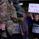 A family member holding a "welcome home" sign. (Mark Less/KSL TV)