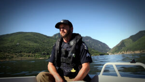Officer rides in a boat in a mountain lake