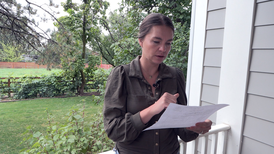 woman reads paperwork on her porch...