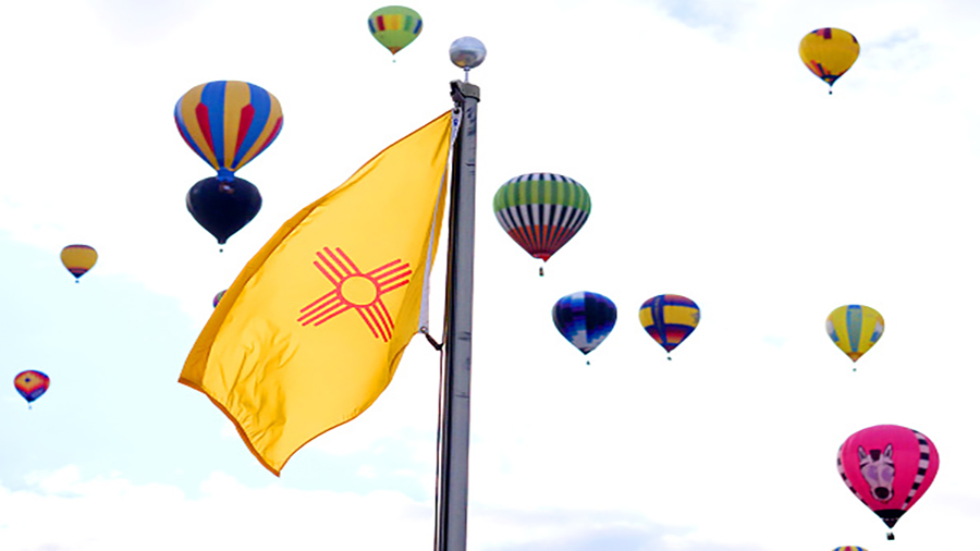 ALBUQUERQUE, NM - OCTOBER 9: Balloons fly past the New Mexico state flag during the 2018 Albuquerqu...