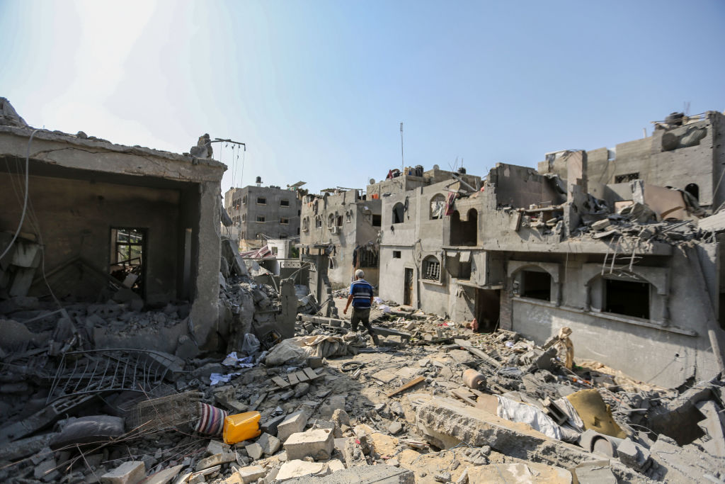 A local citizen searches through buildings which were destroyed during Israeli air raids in the sou...
