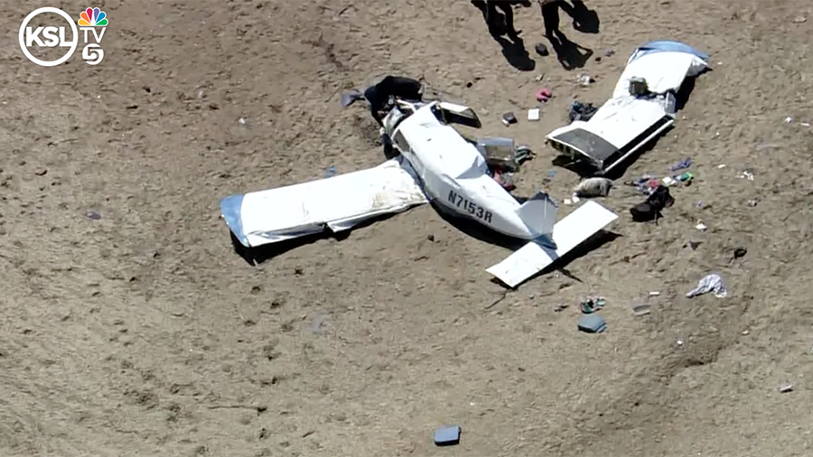 white plane in pieces on dry brown terrain...