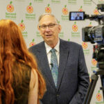 Elder Vern P. Stanfill of the Seventy speaks to a journalist after presenting a check of nearly US$1 million to Second Harvest of the Big Bend CEO Monique Ellsworth on Monday, October 23, 2023, in Tallahassee, Florida. (The Church of Jesus Christ of Latter-day Saints)