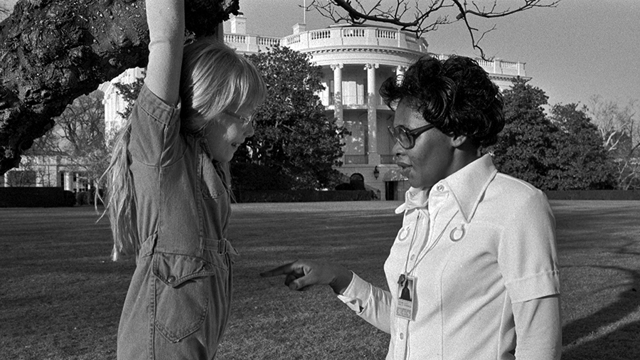 A woman talks to a little girl hanging from a tree in front of the White House...