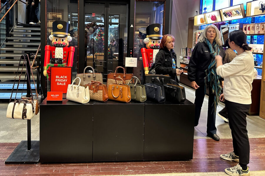 Shoppers pause near a display of handbags at a Coach store in New York on Sunday, Nov. 19, 2023. Re...
