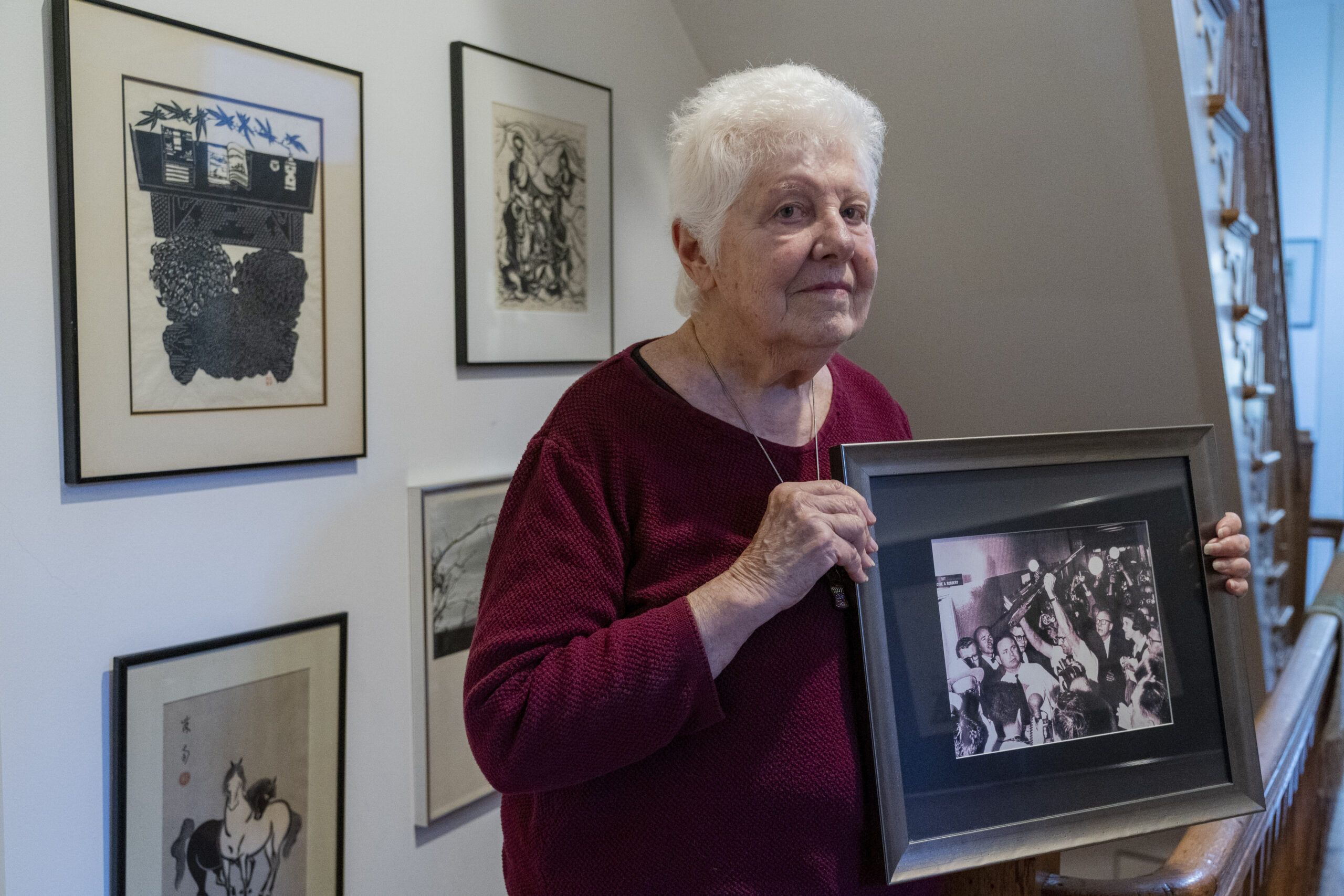 Peggy Simpson holds a photograph of law enforcement carrying Lee Harvey Oswald's gun through a hall...