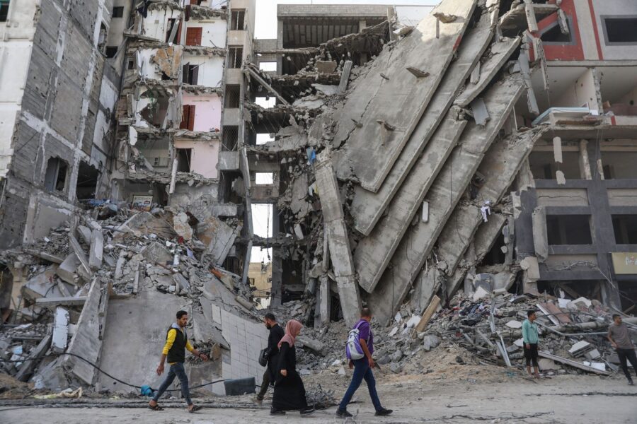 Palestinians walk through damaged buildings in Gaza City. (Mohammed Hajjar, Associated Press)...