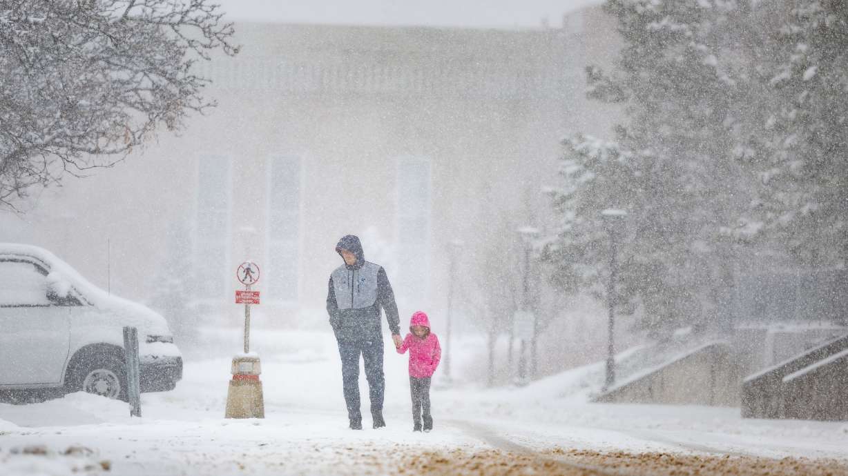 Brock Peery and his daughter Berkley, 6, walk back to their car during a snowstorm in Salt Lake Cit...