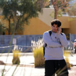 A University of Nevada, Las Vegas, student talks on his cellphone after a shooting reported on campus, Wednesday, Dec. 6, 2023, in Las Vegas. (AP Photo/Lucas Peltier)