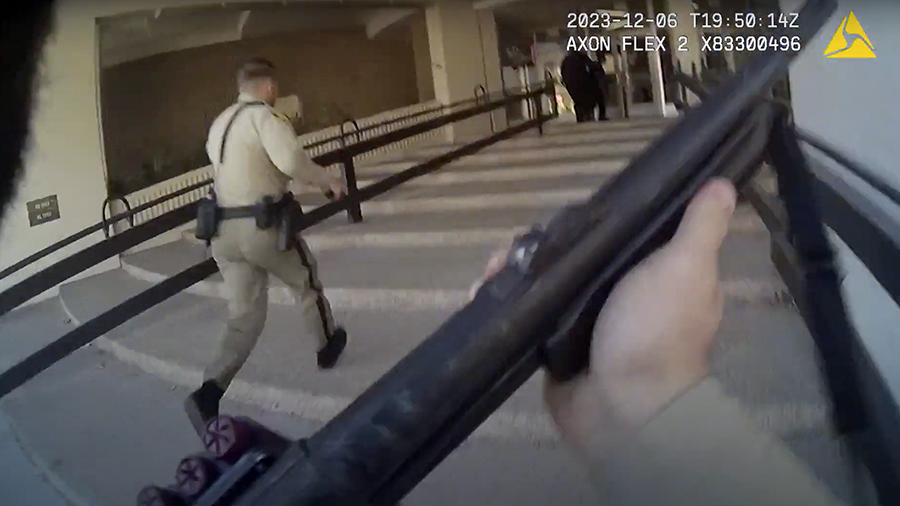 one officer walks, a body camera shows that officer holding a two-handed firearm...