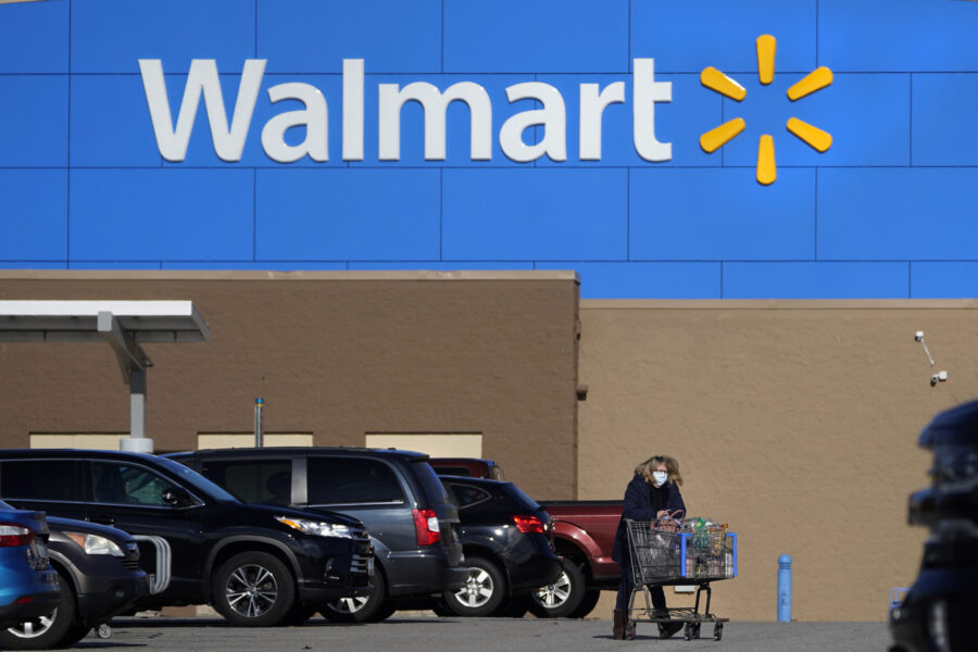 FILE - A woman wheels a cart with her purchases out of a Walmart store, Nov. 18, 2020, in Derry, N....
