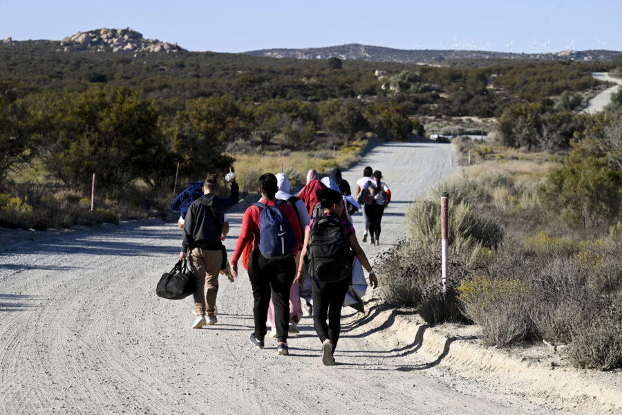 FILE - Asylum-seekers walk to a U.S. Border Patrol van after crossing the nearby border with Mexico...