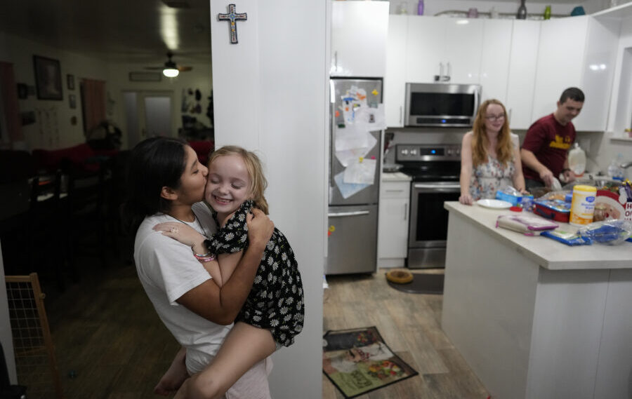 Sol, left, a 14-year-old from Argentina, kisses 8-year-old Maddie Hazelton as they play together in...