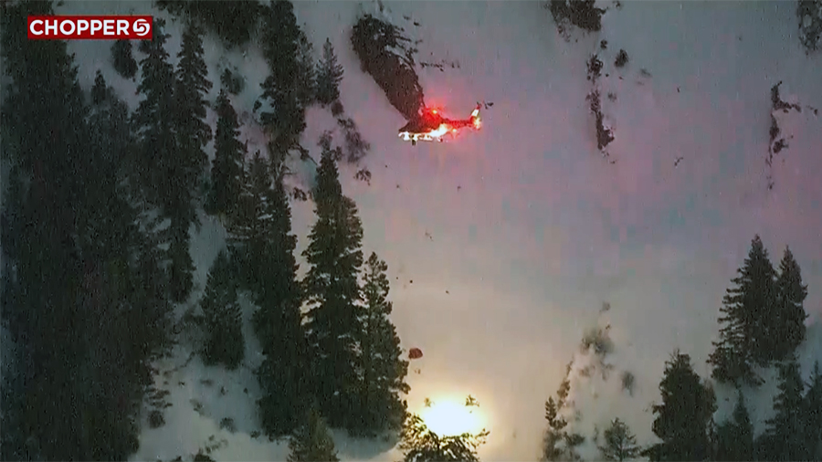 helicopter hovers above a paraglider crash on a snow-covered mountain...