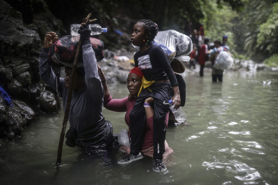 Haitian migrants wade through water as they cross the Darien Gap from Colombia to Panama in hopes o...