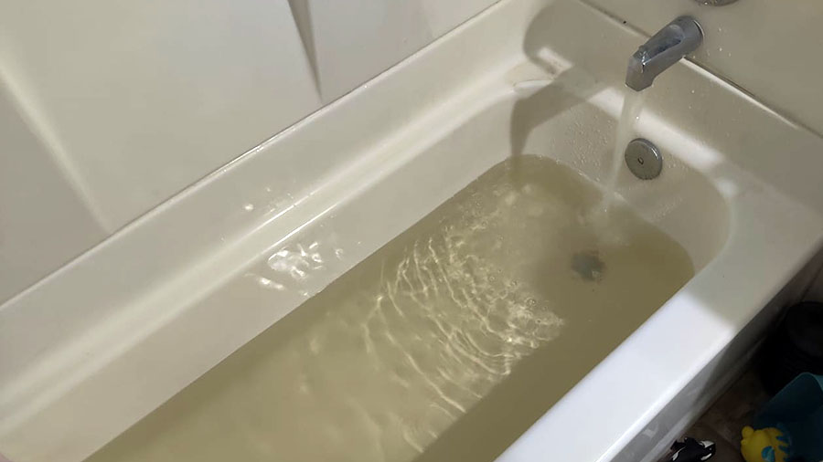 a bathtub with yellow or brownish tinted water...