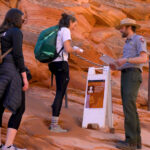A Ranger chats with visitor and checks their permit near the section of the trail that has chains and leads to Angels Landing. (Abi Farish, NPS)