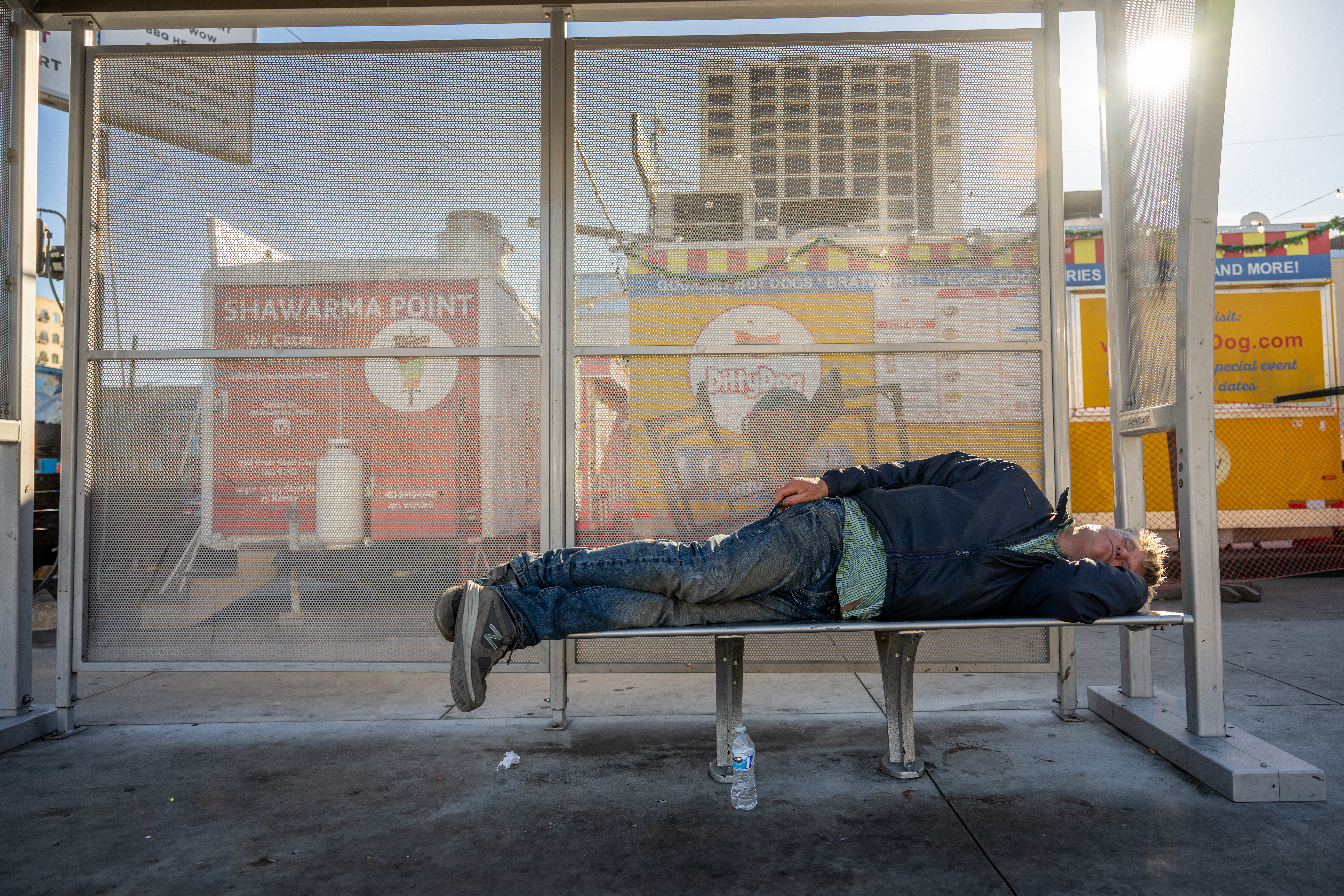 DECEMBER 18: An unhoused person sleeps on at a bus stop on December 18, 2023 in Austin, Texas. The ...