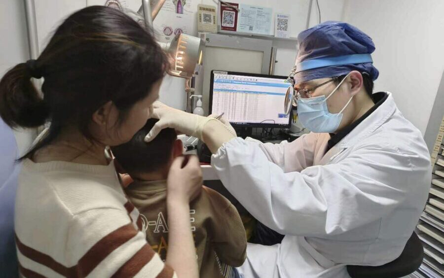 In this photo provided by researchers in January 2024, Dr. Yilai Shu examines a young patient at th...