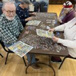 Seniors at separate tables getting sections of the puzzle put together. (Courtesy: The Springville Senior Center)  