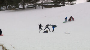 A sledder jumping over a another sledder, almost getting hit at Sugar House Park.