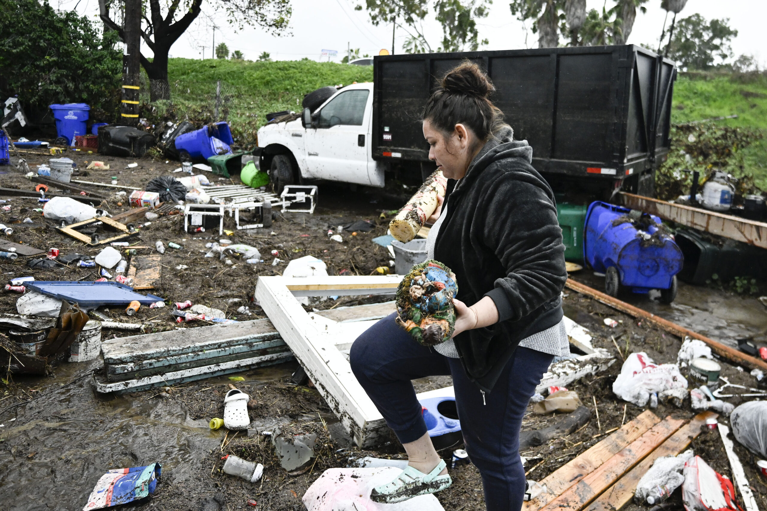 Marlene Sanchez-Barriento salavages items behind her home damaged by flooding, Tuesday, Jan. 23, 20...