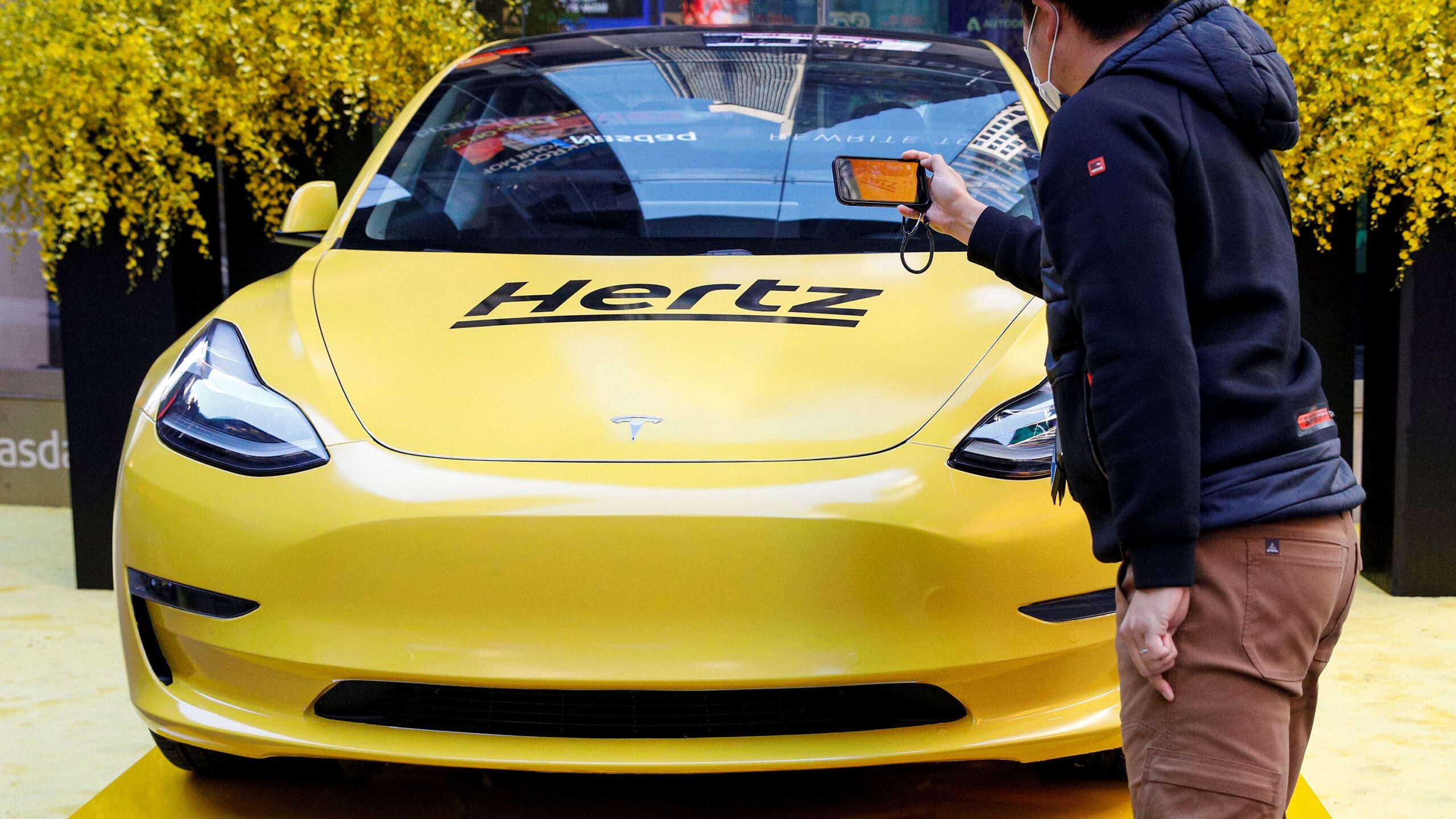 A man photographs a Hertz Tesla electric vehicle displayed during the Hertz Corporation IPO at the ...