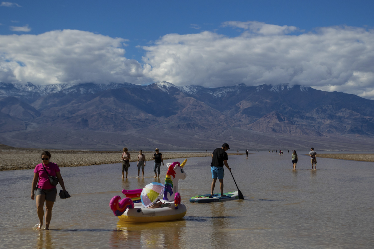 A paddle boarder tows an inflatable unicorn on a temporary lake in Death Valley on Thursday, Feb. 2...