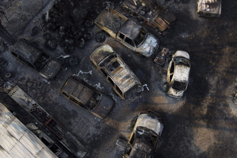 Charred vehicles sit at an auto body shop after the property was burned by the Smokehouse Creek Fir...